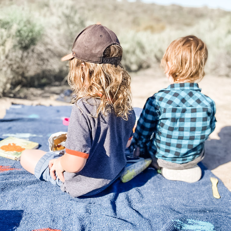 Two little ones sitting on a picnic blanket
